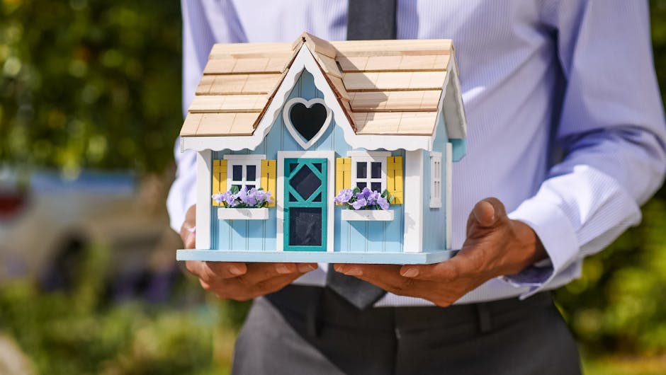 A businessman holds a detailed, colorful miniature house model. Ideal for concepts of real estate and property investmen