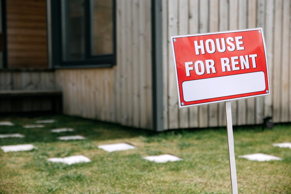A modern wooden house with a prominent  House for Rent  sign in the green yard.
